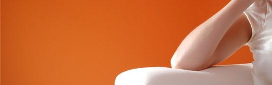 Frau auf Sofa vor oranger Wand im Hintergrund