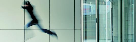 Unschaf belichtete Person springt aus einer Drehtür