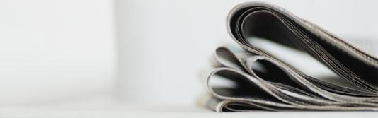 Zeitungen liegen auf einem weißen Sofa