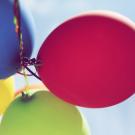 Bunte Luftballone fliegen in einen blauen Himmel