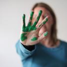 Frau mit grüner Farbe auf Hand mit abweisender Handhaltung