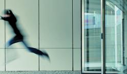 Unschaf belichtete Person springt aus einer Drehtür