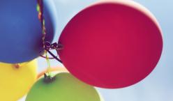 Bunte Luftballone fliegen in einen blauen Himmel