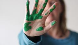 Frau mit grüner Farbe auf Hand mit abweisender Handhaltung